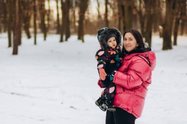 Mother with little daughter in a winter forest. 