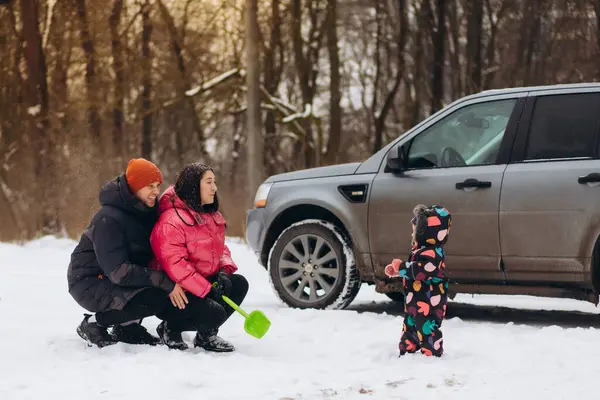 Happy young family is traveling by car in winter forest. People have fun together. Mom, dad and children on winter walk. High quality photo