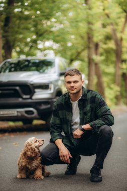 Sonbahar ormanında cocker spaniel köpeği olan bir adam cipin yanında.