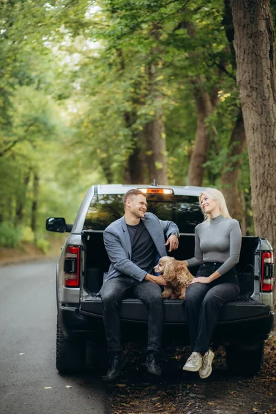 happy couple on vacation in the forest with a dog near the car