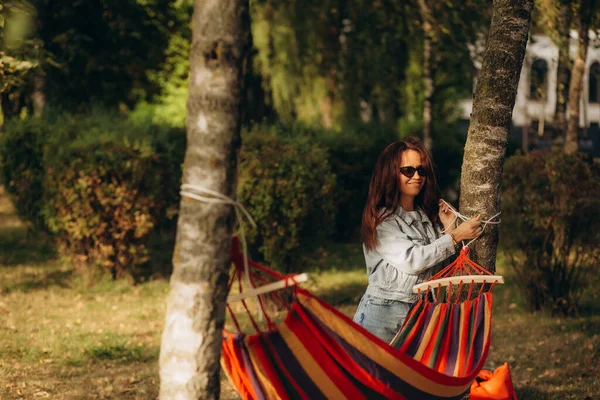 A woman ties a hammock to a tree