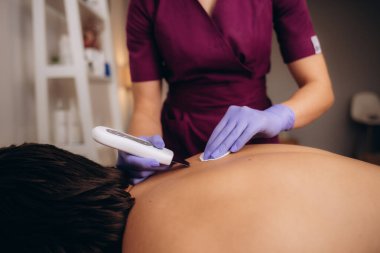 Güzellik salonunda bir adamın sırtının ultrasonik temizlenmesi
