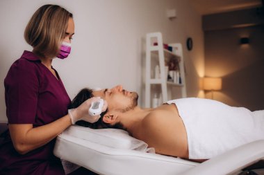 Kozmetik uzmanı spa salonunda adamın yüzüne maske takıyor. Yüksek kalite fotoğraf