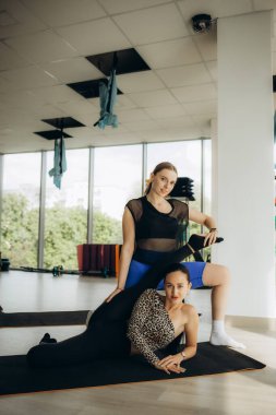 Grup fitness sınıfı. Spor salonunda kızları çalıştıran koç kızın belini tutarak egzersiz yapmanın doğruluğunu gösteriyor. Yüksek kalite fotoğraf