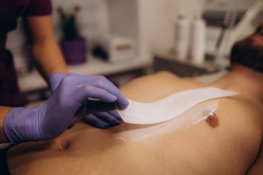 Evde balmumu epilasyon kullanan kıllı bir adamın göğsünü kapatın. Vücut Kılları Çıkarma Cilalama Sıcaklığı. Yüksek kalite fotoğraf