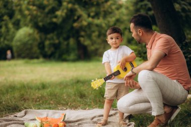 Baba oğluna dışarıda gitar çalmayı öğretiyor. Yüksek kalite fotoğraf