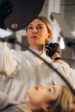 Güzellik uzmanı ayna tutuyor ve müşteriye çizilmiş kaşların sonuçlarını gösteriyor. Kaşlar mikro patinaj konsepti. Corona virüsü salgını sırasında güzellik salonu konsültasyonu. Yüksek kalite fotoğraf