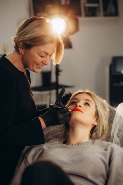 Kalıcı dudak makyajı. Özel renk pigmentli mikropatenli dudak dövmesi kozmetoloji kliniğindeki dudak rengini düzeltir. Yüksek kalite fotoğraf