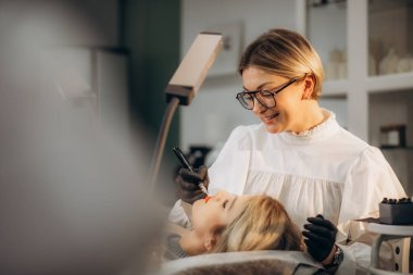 Profesyonel makyaj sanatçısı ve müşterisi dudak kızarma işlemi sırasında. 
