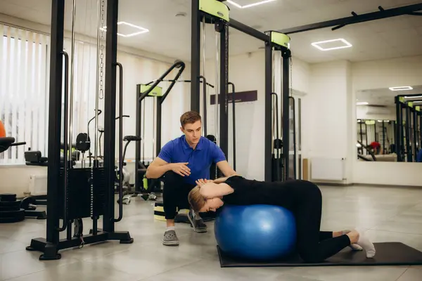  Kadın ve erkek fizyoterapist üniforması giyiyorlar rehabilitasyon merkezinde sağlıklı top kullanıyorlar.. 