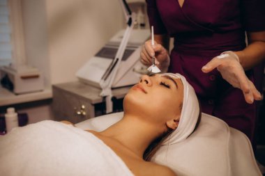 Güzellik salonunda kadın yüzüne maske takan bir kozmetikçi. Yüksek kalite fotoğraf