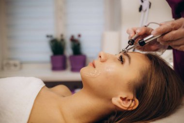 Kadın mikro akım yüz gerdirme ameliyatı oluyor. Yaşlanmayı önleyen bir güzellik uzmanı, yüz sıkılaştırma ve tonlama yapıyor. Yüksek kalite fotoğraf