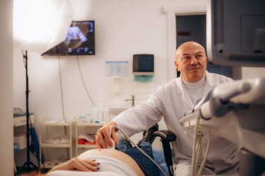 Sonograf iş yerinde ultrason makinesi kullanıyor. Modern klinik tanı ve tedavi. Doktorun elinde ultrason tarayıcısı var. Doktor ultrason hastanede kadın hasta karnını muayene ediyor. Yüksek kalite fotoğraf