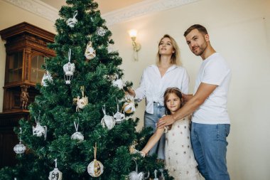 Noel ağacı süslemek. Mutlu aile babası, anne oğul ve küçük kız hep birlikte oturma odasındaki Noel ağacını süsleyin..