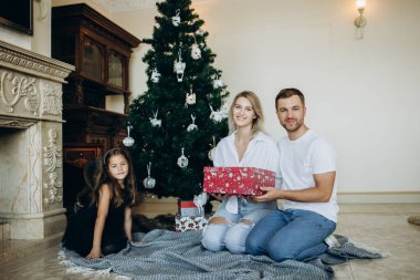 Aile Noel ağacının yanında hediyeler açar.