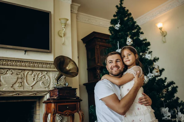 Evde Noel ağacının yanında babasının omzunda oturan komik kız.