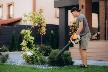 Bahçıvan bahçede yaprak üfleyicisini kullanıyor. Yüksek kalite fotoğraf