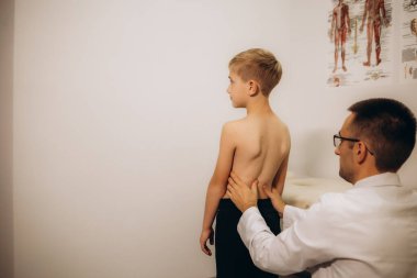 Ortopedist, çocuğun muayenesini klinikte yapıyor. Skolyoz tedavisi.