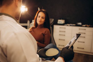 Caucasian woman and plastic surgeon touching and choosing breast implants. 
