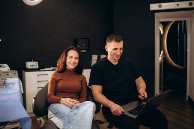 Yakışıklı doktor kadın için bir Danışma verirken bir laptop kullanıyor. Güzel kadın doktor notlar yapıyor. 