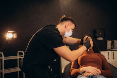 Klinikte ameliyat öncesi genç bir kadının yüzünü muayene eden estetik cerrah. Yüksek kalite fotoğraf