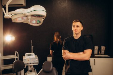 Profesyonel cerrahın portresi kameraya bakıyor ve başarılı bir ameliyattan sonra gülümsüyor. Arka planda modern hastane ameliyathanesi. 