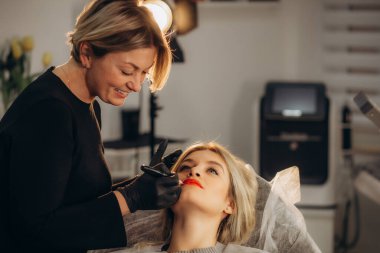 Kalıcı dudak makyajı. Özel renk pigmentli mikropatenli dudak dövmesi kozmetoloji kliniğindeki dudak rengini düzeltir. Son derece yakın çekim. Yüksek kalite fotoğraf