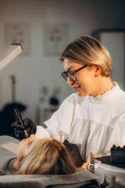 Dövme salonunda kalıcı olarak dudak makyajı yapılan genç bir kadın, yakın plan. Yüksek kalite fotoğraf