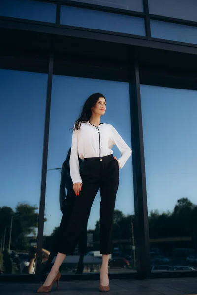 stock image a fashionable woman near the big glass wall of the building. High quality photo