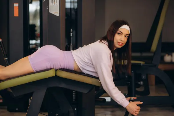 Unrecognizable woman exercising with leg curl machine in gym. High quality photo