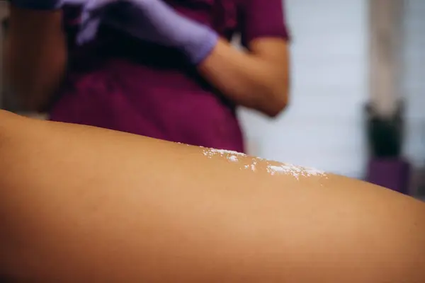 Cosmetologist hand is sprinkling talcum powder on armpit of young woman before the depilation procedure. Epilation and sugaring of armpit. High quality photo. High quality photo