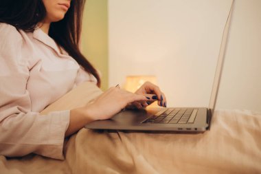 Yatakta dinlenirken dizüstü bilgisayar kullanan çekici genç bir kadın. Yüksek kalite fotoğraf