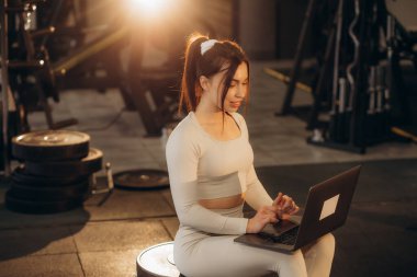 Kadın antrenör spor salonunda uzaktan antrenman yapıyor.