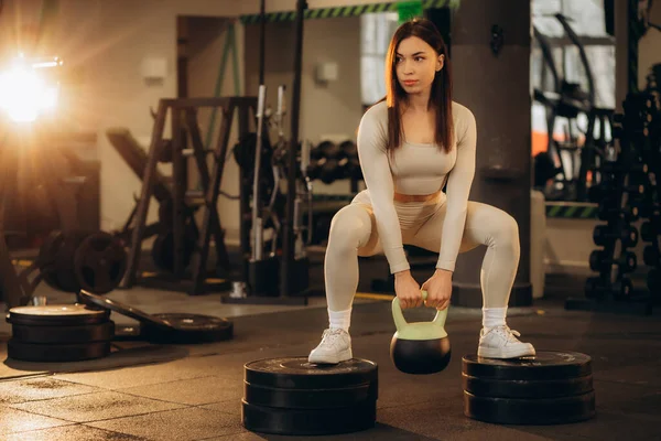 Woman exercise workout at gym fitness training sport with kettlebells weight lifting and legs squat healthy lifestyle bodybuilding. High quality photo
