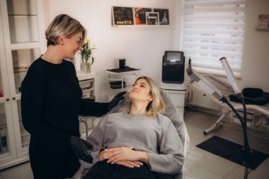 Kalıcı makyaj ustası müşterilerine kaş mikroplu patinaj ve dudak kıvrımlı dövme sonuçlarını gösteriyor. Yüksek kalite fotoğraf