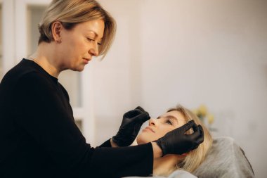 Kız güzellik uzmanı ipek kaş dövmesinin yardımıyla damgalanıyor. Kalıcı makyaj. Kalıcı kaş dövmesi var. Yüksek kalite fotoğraf