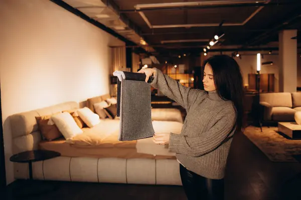 The woman chooses the fabric on the sofa. A young women looks at tissue samples. Selects the color of the sofa. Textile industry background. Tissue catalog. High quality photo