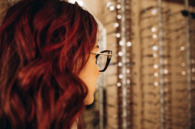 Modern optik mağazada gözlük çerçevesi seçen güzel ve modaya uygun bir kadın. - Evet. Yüksek kalite fotoğraf