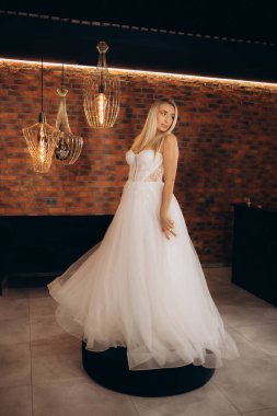 Başka bir gelinlik tutan, gelinliği gelinlik salonunda seçen, düğüne hazırlanan, gelinlik konseptini seçen güzel beyaz bir kız. Yüksek kalite fotoğraf