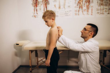 Pediatrik nörolog, sırt ağrısı olan 5 yaşındaki bir kızın sırtını muayene ediyor. Çocuklarda kas ağrısı ve skolyoz tedavisi. Yüksek kalite fotoğraf
