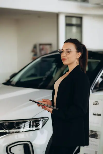 Young saleswoman with tablet in a car showroom. High quality photo
