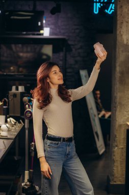 Bir kadın elektronik mağazasında fotoğraf makinesinde selfie çekiyor.