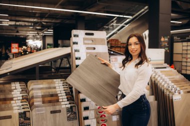 Koyu renk saçlı, yönetici veya satıcı pozisyonundaki güzel genç bir kadın küçük bir mağazada farklı renkte ve tipte görünüyor. Yüksek kalite fotoğraf
