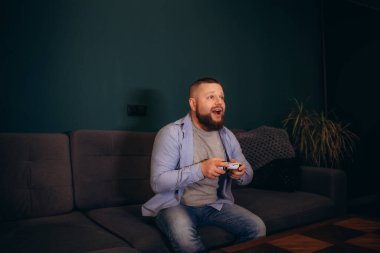 Genç mutlu adam hafta sonları gülüyor ve video oyunları oynuyor. Yüksek kalite fotoğraf