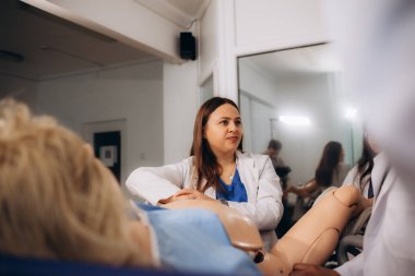 Öğretmen, doğum uzmanı ve jinekolog öğrencileri için pratik bir seans düzenler.