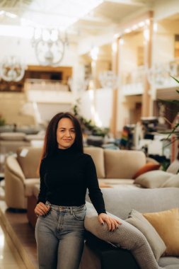 Mobilya dükkanında kanepe ve yastık seçen genç bir kadın. Yüksek kalite fotoğraf. Yüksek kalite fotoğraf