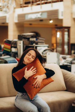 Mobilya dükkanında kanepe ve yastık seçen genç bir kadın. Yüksek kalite fotoğraf