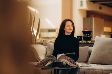 Kadın kanepedeki kumaşı seçiyor. Genç bir kadın doku örneklerine bakıyor. Kanepenin rengini seçer. Tekstil endüstrisi geçmişi. Doku kataloğu. Yüksek kalite fotoğraf. Yüksek kalite fotoğraf