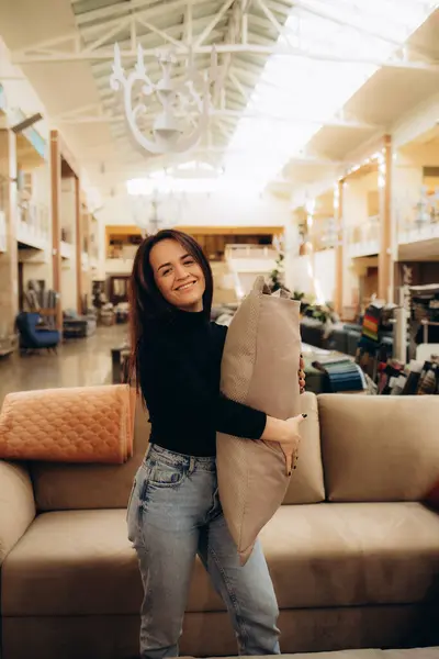 stock image Young woman choosing sofa and pillow in furniture store. High quality photo