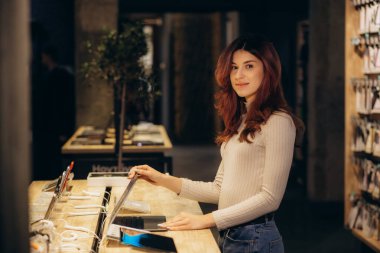 Bir kadın bir elektronik mağazasında dizüstü bilgisayar arıyor.